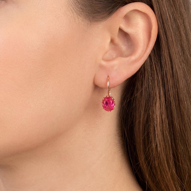 A vintage pair of 14k rose gold dangle earrings featuring oval-cut synthetic ruby stones. The earrings are set in elegant...