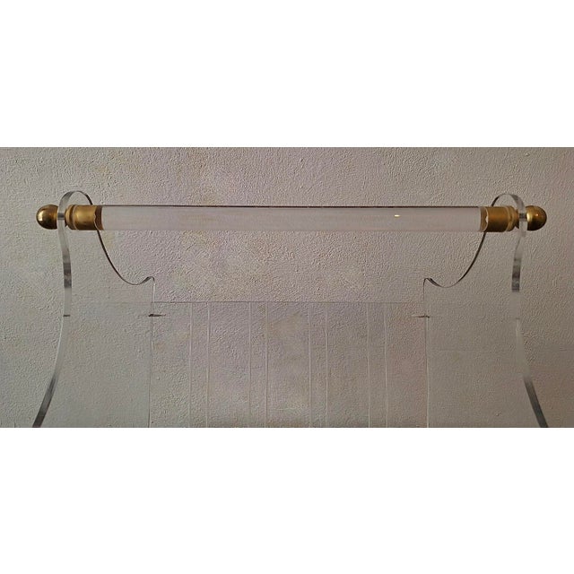 Fine magazine rack, shaped curved acrylic frame and handle with two decorative brass supports. Dates from the 1970s.