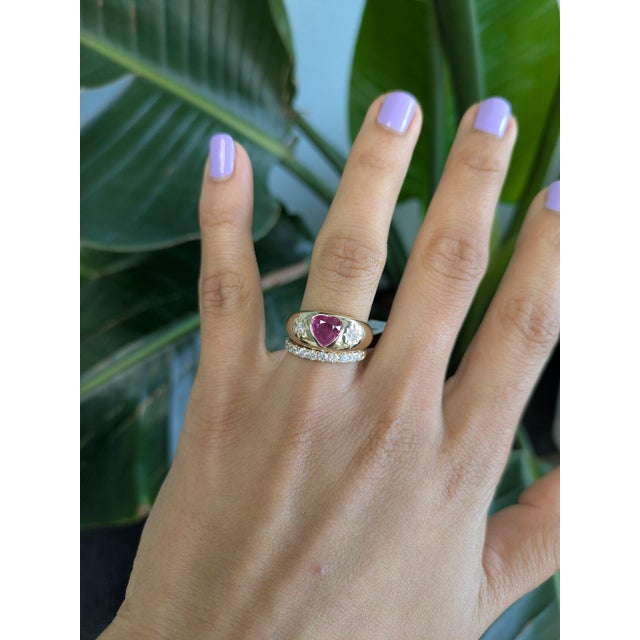 A natural pink sapphire glows in a soft, romantic pink at the centre of this solid 14K yellow gold ring, cut as a heart...