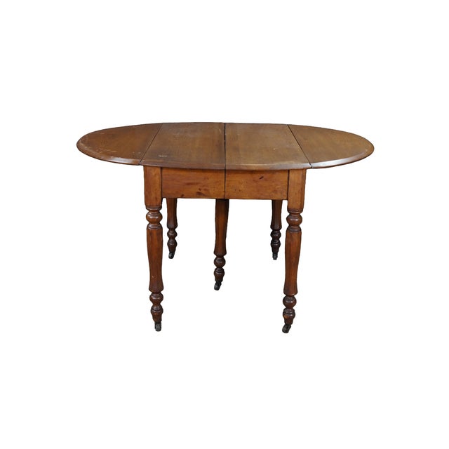 An antique Victorian era drop-leaf table, constructed from solid mahogany wood with a warm, naturally aged patina. The...