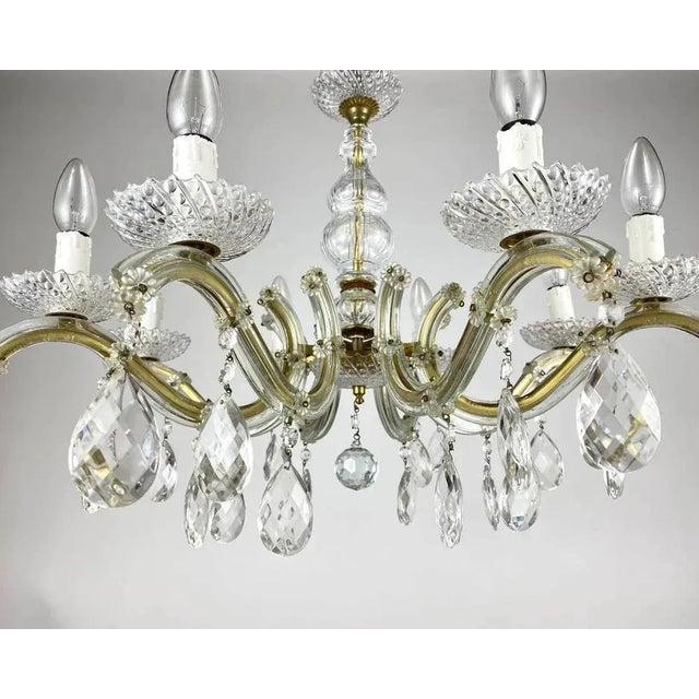 Circa 1970s maria theresa style chandelier with eight candle arms. germany. the framework is in golden brass, surrounded...