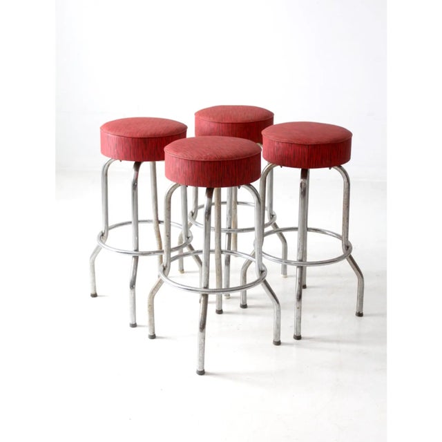 Set of four vintage bar stools with a classic single ring design. Chrome legs provide a clean, streamlined look, while red...