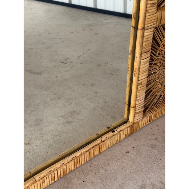 A stunning monumental vintage Buri and rattan wall mirror showcasing six beautifully handwoven sunburst panels that frame...