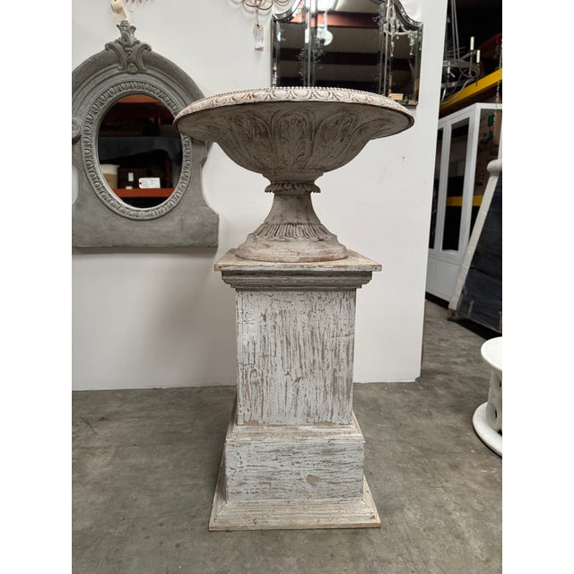 Iron urn on wooden pedestal. Total height 61". Urn is 36" wide by 21" tall. Pedestal is 26" at the base, 23" at the top,...