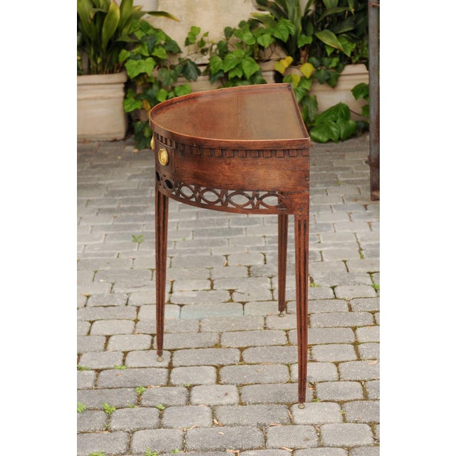 An English oak demilune console table from the mid-19th century, with tray top, single drawer and tapered legs. Born in...