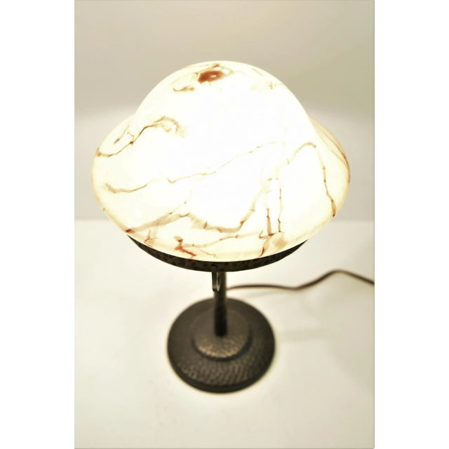 A nice art nouveau hammered wrought iron table lamp and a beautiful pink/Cream coloured glass shade made in a marble...