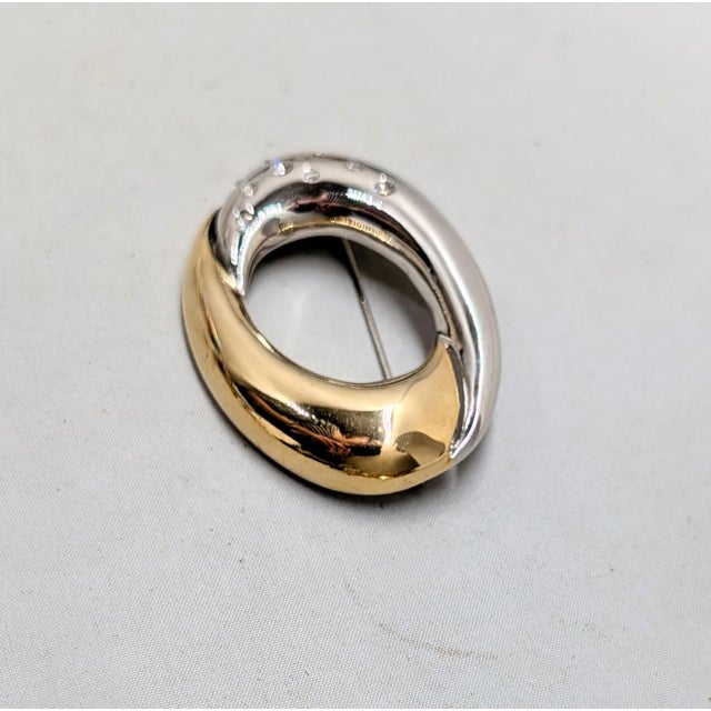 1980s oval cut out half rhodium plated with inset round clear rhinestones and half goldtone brooch with security clasp....