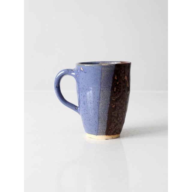 This vintage handmade studio pottery mug showcases an organic form, an earthy glaze, and a generously proportioned handle...