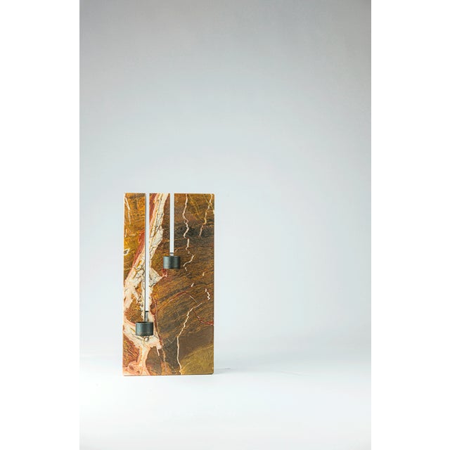 In Levature, the solidity of the stone is traversed by two precise incisions that accommodate burnished metal elements,...