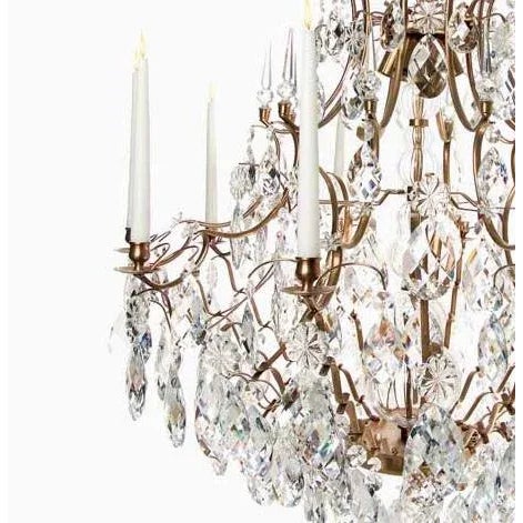 A baroque chandelier in light brass (cognac colour) with 10 outer arms for wax candles and 6 electric bulb fittings on the...