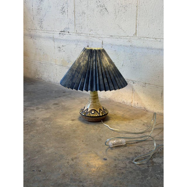 A sculptural flared base and a pleated shade give this compact table lamp a classic organic silhouette. Vibrant glazed...