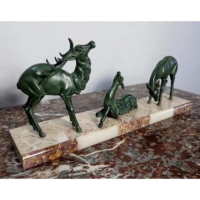 Group in regula with green patina representing a stag accompanied by two hinds on a base in ochre marble girdled on the...