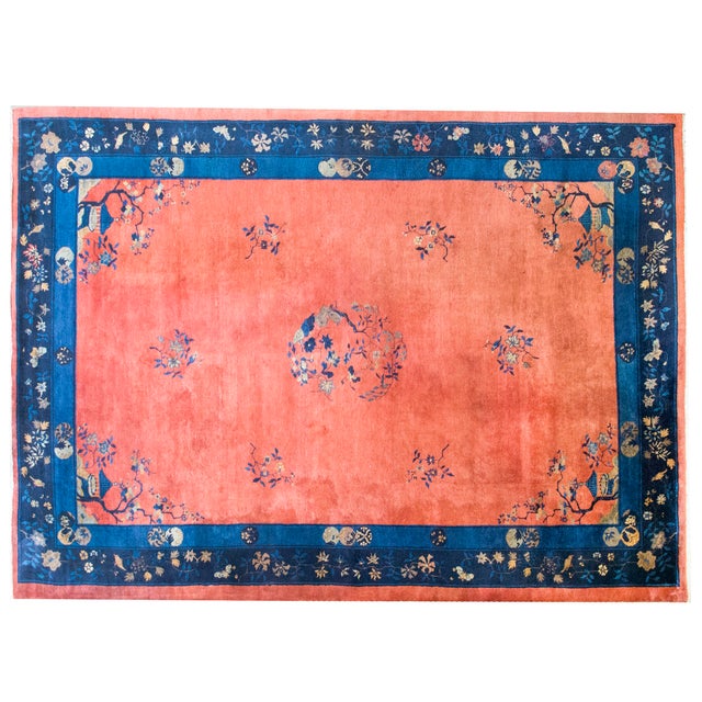 This hand-woven Chinese Art Deco rug from the 1920s features a vibrant coral field adorned with traditional floral sprays...