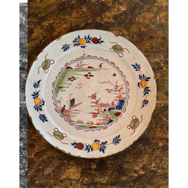 Tin glazed earthenware plate painted in polychrome with a chinoiserie landscape at the center, showing a pavilion, sailing...