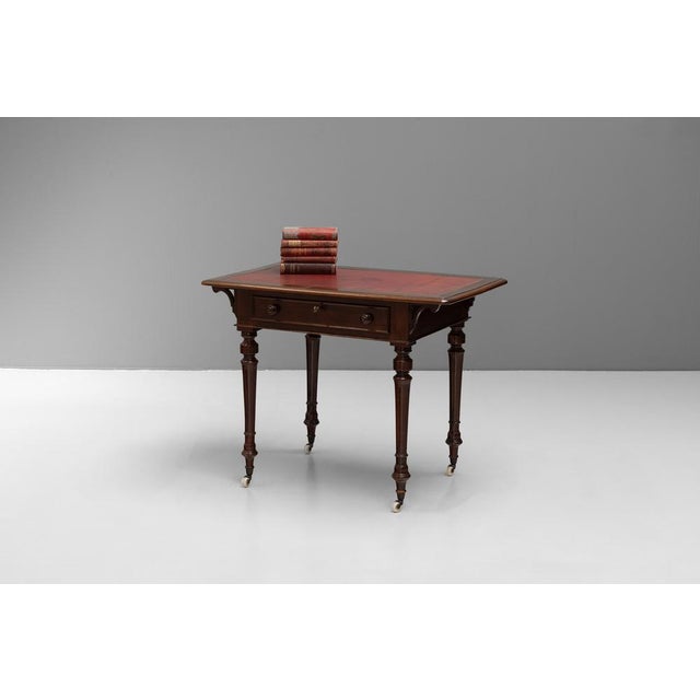 Double sided Victorian walnut side table with inset leather top on turned legs with original casters. Circa 1880.