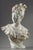 Bust of a beautiful woman in a corset held in place by a bow, with her face turned to the side exposing her profile. This...