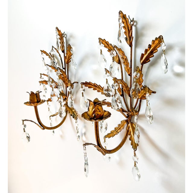 Stunning pair of mid 20th century Italian gilt tole wall sconces, each adorned with cascading faceted crystal prisms....