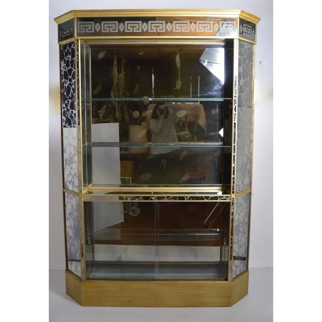 Tall and narrow form églomisé mirrored back bar. Open shelved top, storage with sliding glass door storage on the bottom....