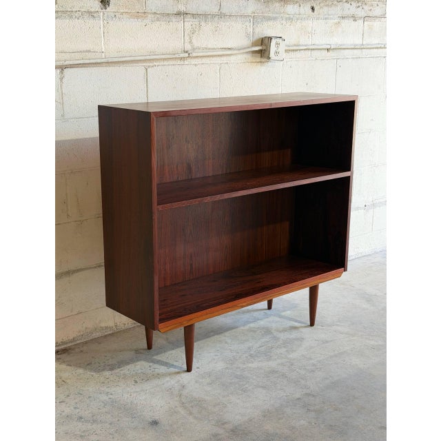 This elegant mid-sized shelf unit features an open-face upper display section sitting directly above a low interior...