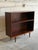 This elegant mid-sized shelf unit features an open-face upper display section sitting directly above a low interior...