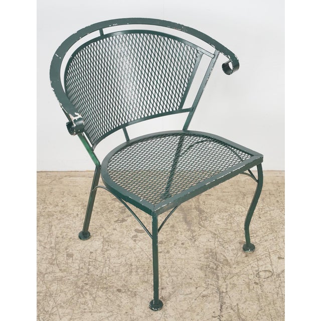 Mid Century style patio chairs made of painted green wrought iron. They feature a barrel backrest and slanted seats with a...
