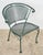 Mid Century style patio chairs made of painted green wrought iron. They feature a barrel backrest and slanted seats with a...