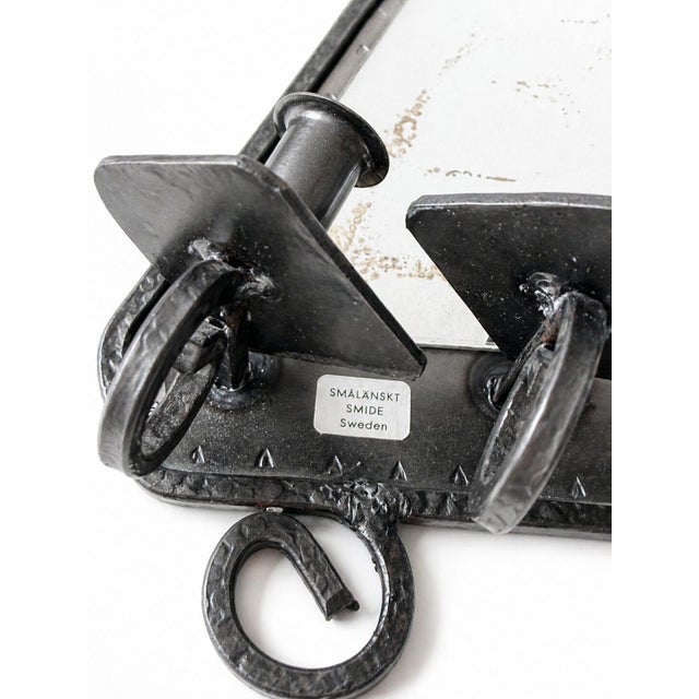 Striking vintage Swedish wall candle holder with mirror backplate, hand-forged by Smålandskt Smide during the 1960s–1970s....