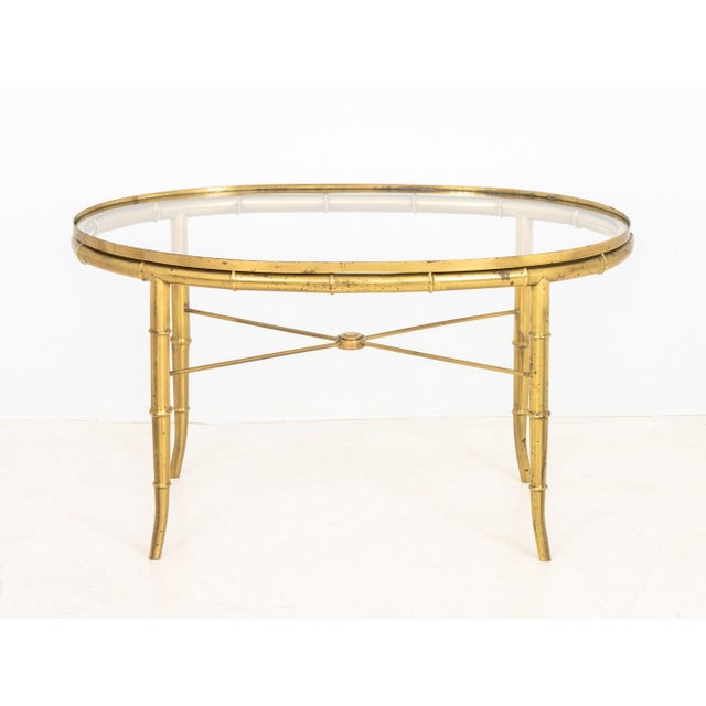 Maison Jansen Style Faux Bamboo Brass Oval Glass Top Coffee Table, on four splayed legs conjoined by X-form stretcher....