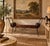 Striking vintage rustic bench featuring an elegant wrought iron frame with dramatic scrolled arms and decorative ironwork...