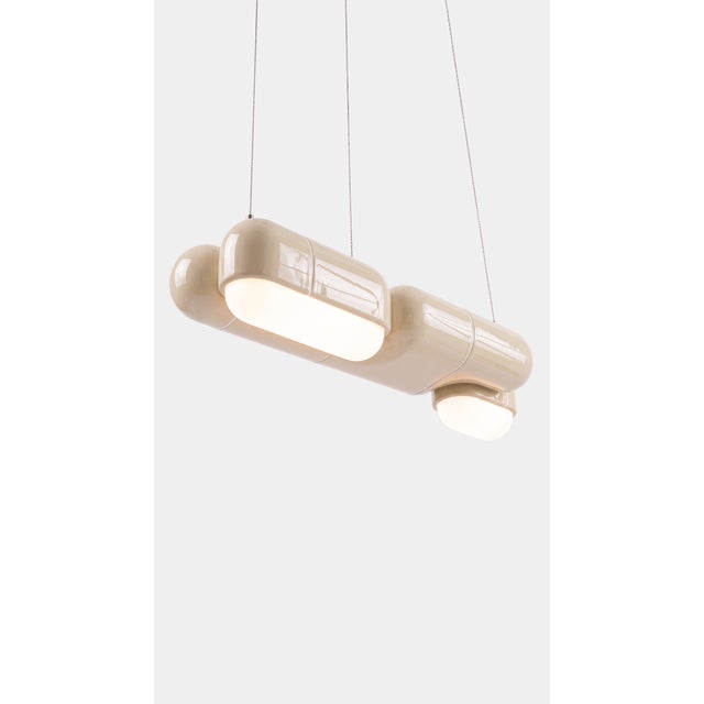 A linear pendant made for the table everyone gathers around. The curved-tile module repeats along its length, so light...