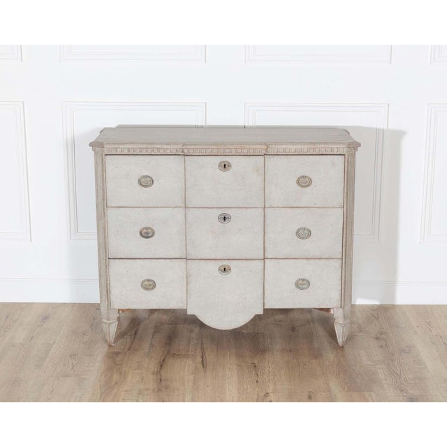 This Gustavian-style chest of drawers is a refined example of Swedish neoclassical design, crafted in pine and finished in...