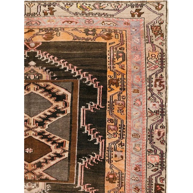 This Mid-20th century Turkish Anatolian wide gallery runner features a vertically organized composition set against a deep...