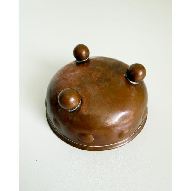 Antique, circa early 1900s, small-scale hammered copper bowl with three ball feet and embossed circle pattern around the...