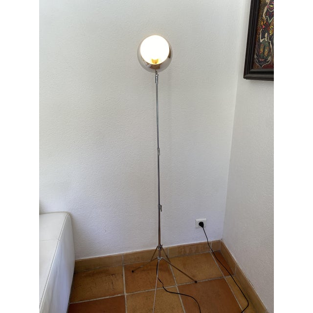 Adjustable telescopic tripod floor lamp. Shaped like an eyeball, in a Space Age style, the lampshade tilts to the desired...