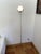 Adjustable telescopic tripod floor lamp. Shaped like an eyeball, in a Space Age style, the lampshade tilts to the desired...