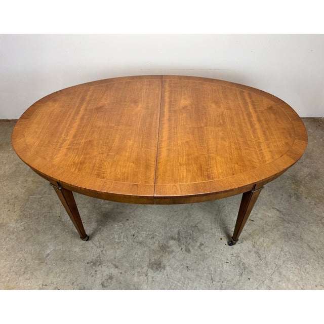 A beautiful Baker Furniture Federal / Regency style dining table on casters with inlaid walnut and three 18” leaves. Circa...