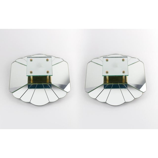 Pair of wall lamps, by Alain Delon for Sabot, 1970s. Wooden structure covered with ground and shaped mirror elements,...