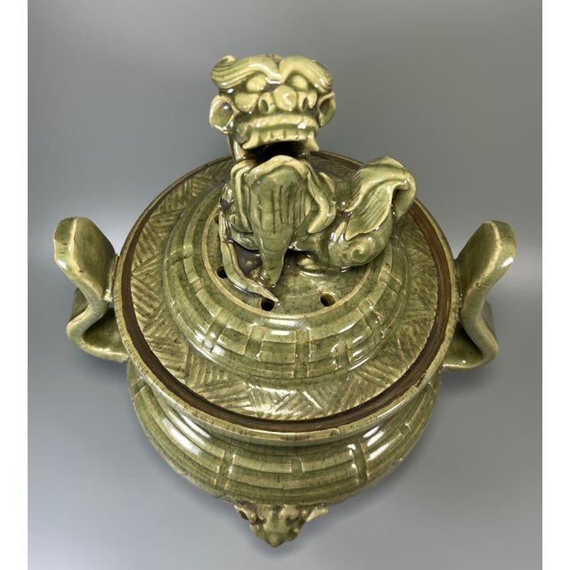 Impressive Chinese celadon lidded tripod censer. Topped with a detailed lion‑form finial on the cover, paired with elegant...