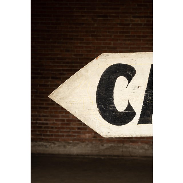 Single-sided hand-painted wooden sign in an arrow format, advertising nearby cabin lodging just a quarter mile ahead. Bold...
