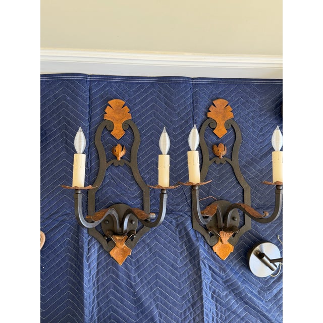 An authentic pair of Paul Ferrante Model 1000 two-light wall sconces, handcrafted from forged iron with hand-hammered...