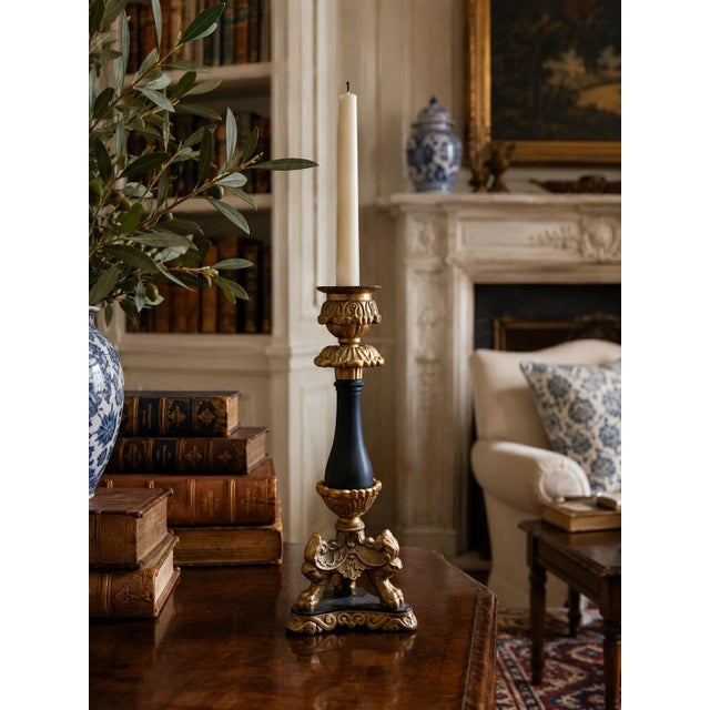 A sculptural late-20th-century candlestick composed of warm brass ornament and a contrasting black central stem. The...