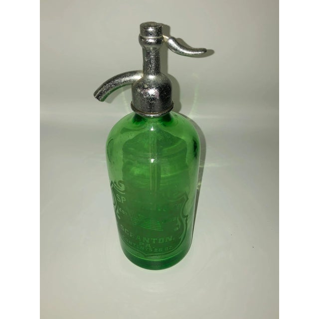 A green glass Spitzer and Company seltzer bottle displaying the American flag. Established 1838, 26 ounces.
