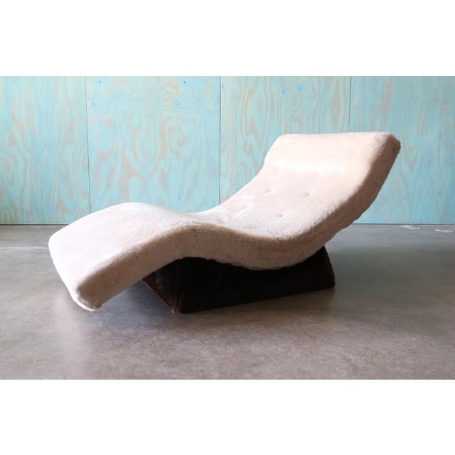 A mid century modern wave style chaise lounge. Sits on a trapezoidal upholstered plinth base. Similar stylings to Adrian...