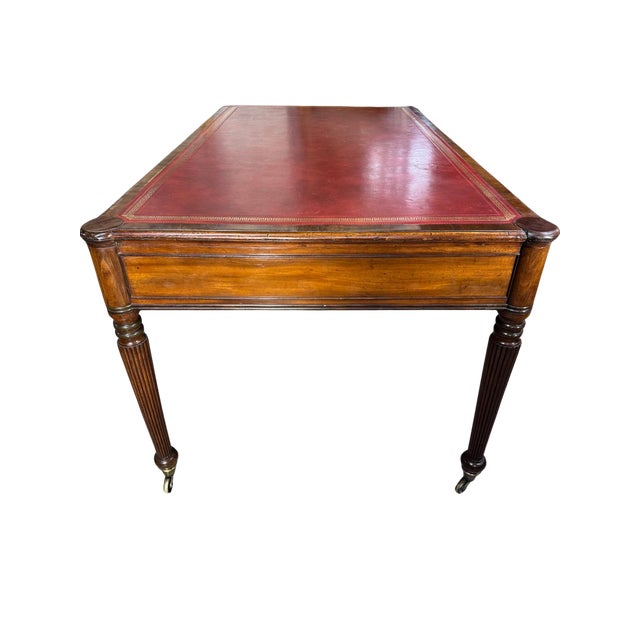 Late 18th century English writing table crafted in warm-toned wood, featuring a classic red leather top with gilt-tooled...