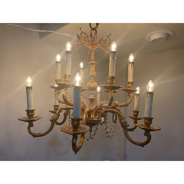 Exquisite vintage twelve light chandelier with its original prism swags. This gilt chandelier has a warm gold finish; and...