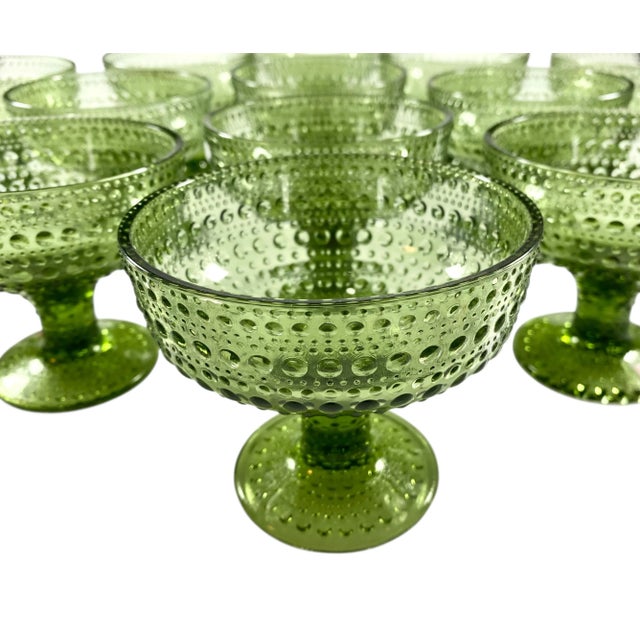 A set of fourteen dark green glass footed dessert bowls in the kastehelmi pattern by iittala. Many unused with the brand...