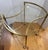 A sleek mid-century bar cart featuring a clean-lined brass frame with an elegant oval silhouette and inset glass top. The...