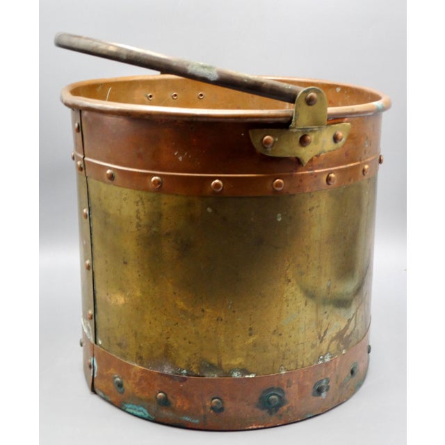 A lovely antique English solid brass and copper bucket with a swing handle. Circa late 1800's, it has decorative rivets...