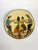 A charming round glazed ceramic dish featuring a figurative scene of four dancers in a circle, wearing stylized...