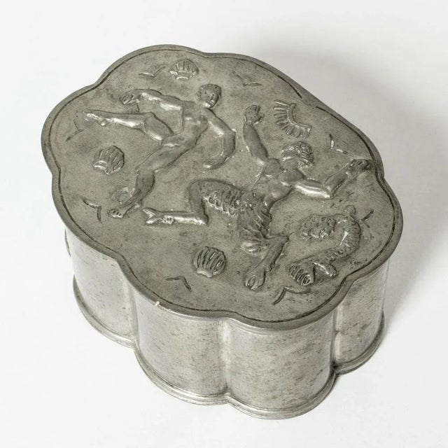 Lovely pewter box from Herman Bergman, in oval shape with a scalloped silhouette. Decor of a lively woman and a faun among...